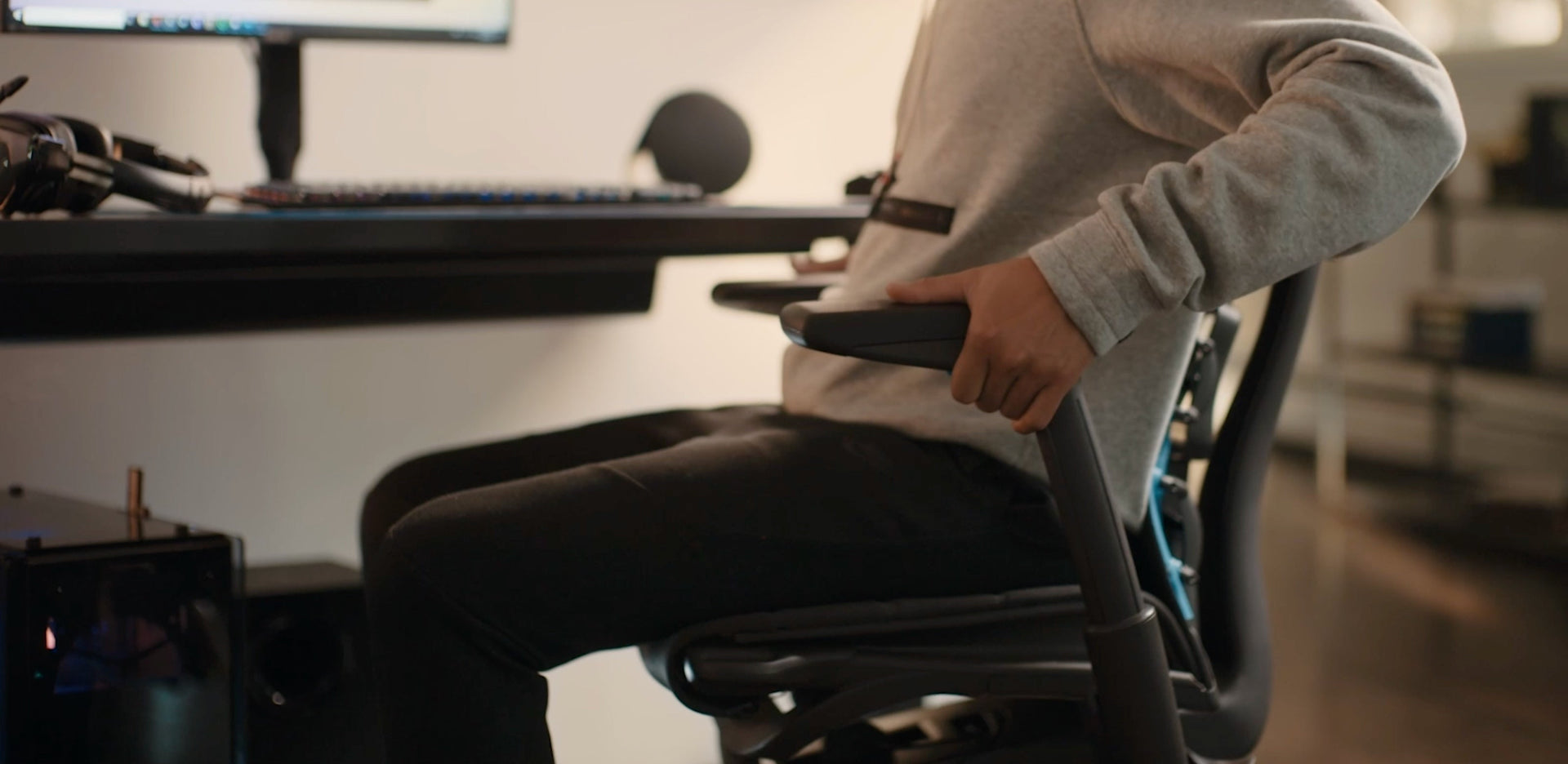 A close-up video of a black Embody Gaming Chair arm being adjusted by a person in front of a desk.