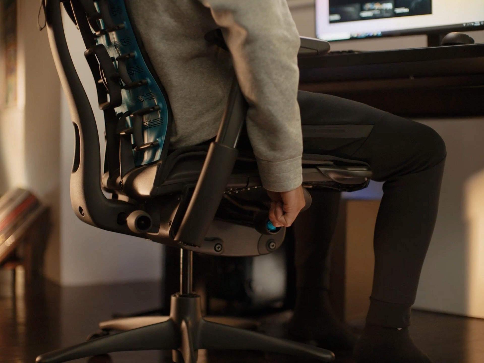 A close-up image of the side of the Embody Gaming Chair with a person adjusting seat height mechanism.