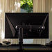 An Ollin Monitor Arm holds up a computer monitor on a gaming desk, viewed from the back in a residential setting.